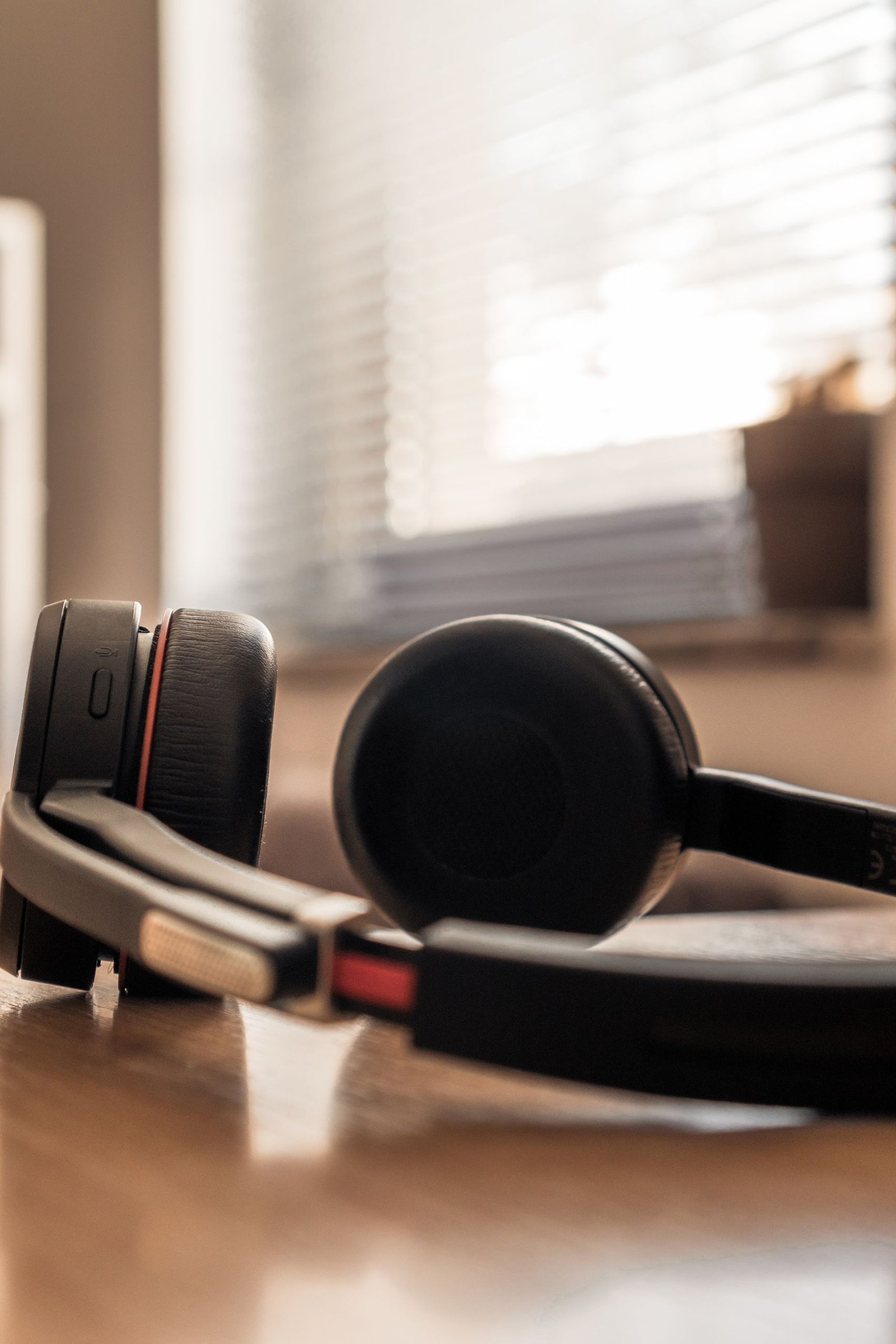 A close-up shot of black headphones on a wooden surface with soft background lighting.