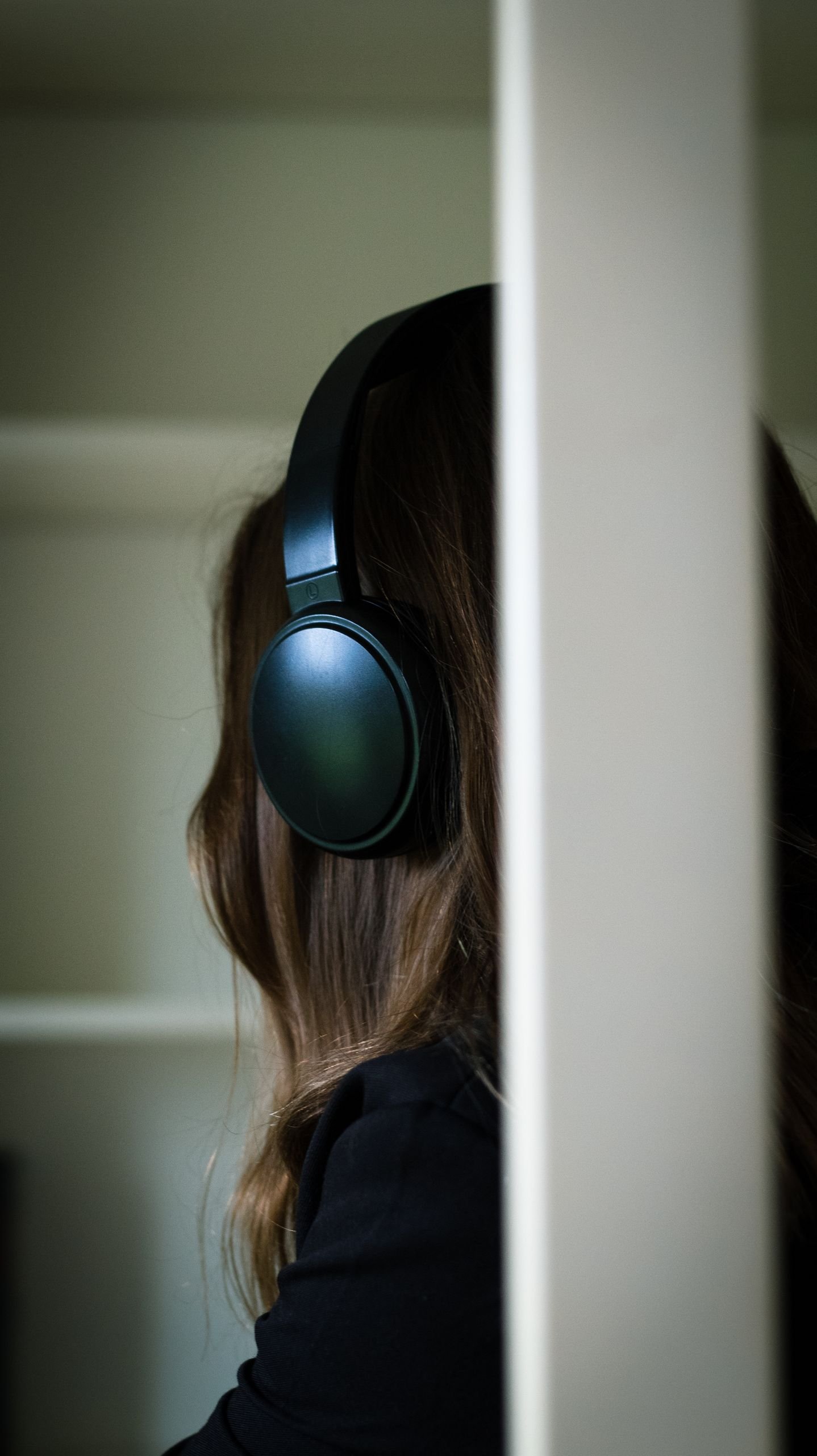 Brunette woman wearing headphones, relaxing indoors, enjoying music.
