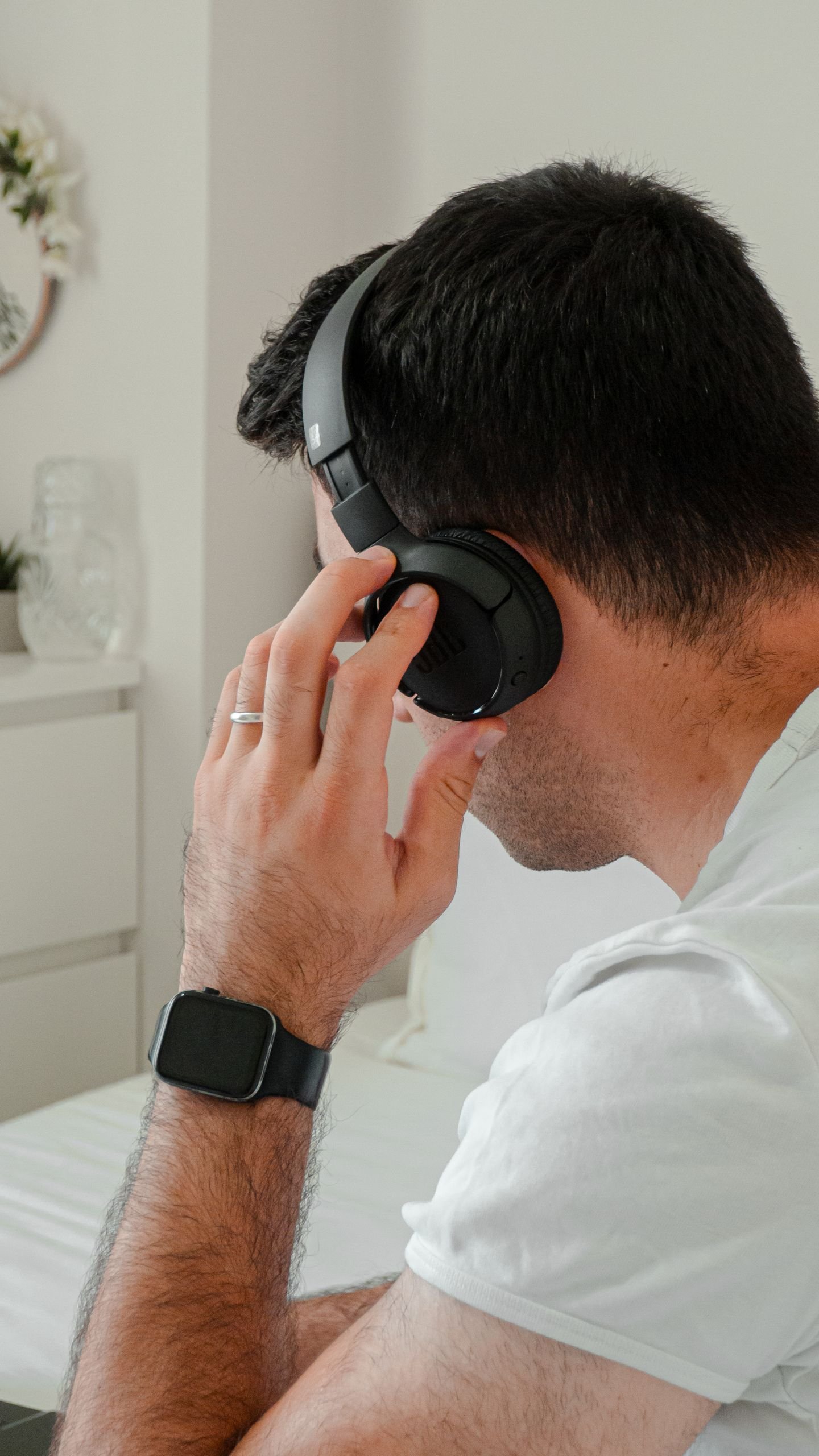 Man wearing headphones and smartwatch, relaxing indoors; perfect for lifestyle and technology themes.