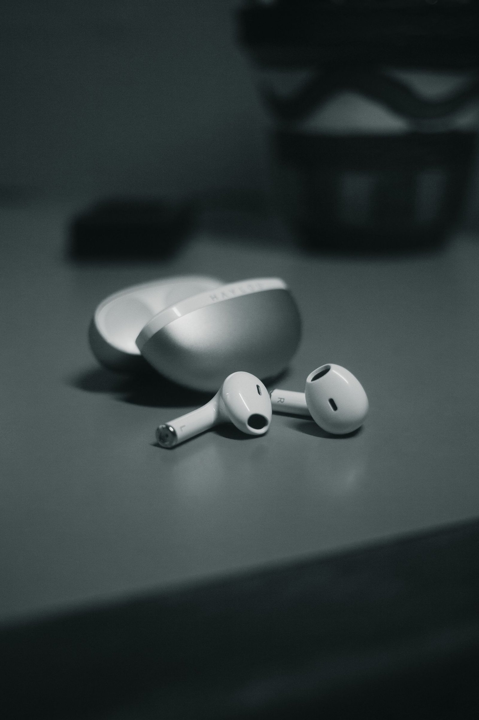 Minimalistic close-up of wireless earbuds with sleek design on a table in monochrome.