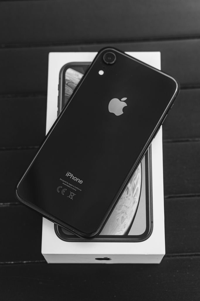 Close-up of a black iPhone on its box, highlighting sleek design in monochrome.