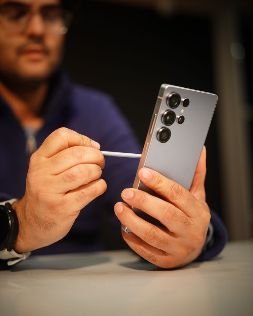 Close-up of a man interacting with a smartphone using a stylus, indoors.
