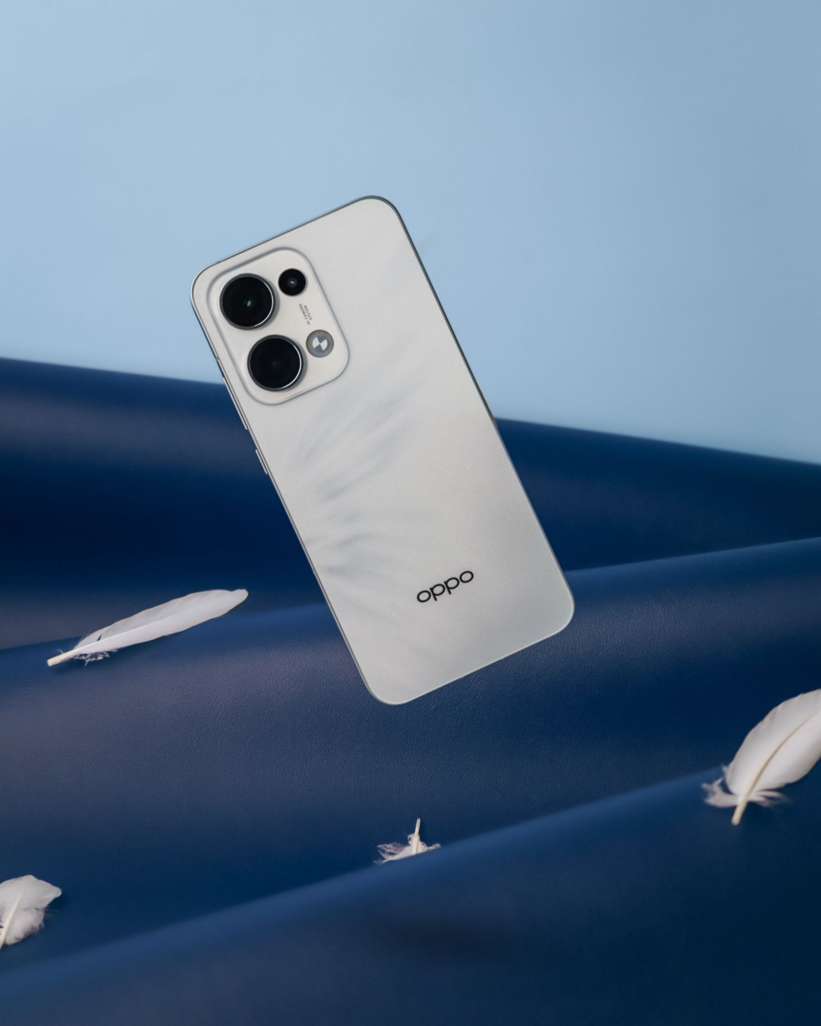 Stylish smartphone against a blue backdrop with floating feathers.